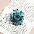 Detailed close-up of a translucent dark teal flower-shaped hair claw clip with glossy resin - Blue Rosebud