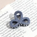 Detail of grey ink-splatter resin hair claw clip resting on vintage newspaper background - Three-Petal Flower / Dark Gray (Splash Ink)