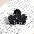 Macro detail of wave-shaped black hair claw clip with silver speckles on vintage book - Wavy Line / Black (Splash Ink)