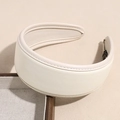Detail van een crème gevlochten lederen hoofdband met gewatteerd design en stiksels - Glad Lederen Stijl / Glad Wit