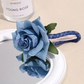 Detail of blue silk rose hair clip with green leaves and mesh handle on white mirror - Blue