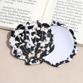 Close-up of a shell-shaped portable makeup mirror with shell texture on fashion book - Black & White