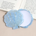 Detailed view of a light blue shell-shaped makeup mirror with golden marble texture - Blue