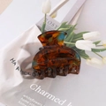 Close-up of elegant amber tortoiseshell hair claw clip on white fabric with tulips - Dark Brown Amber Tortoise Style / Dark Brown