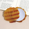 Detailed close-up of shell-shaped folding mirror with tortoiseshell pattern and circular glass - Yellow Brown