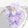 Detailed macro view of purple lily hair claw clip with silk fabric petals on a vintage mirror - Purple