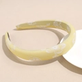 Detail of yellow satin headband featuring white floral patterns and padded fabric design - Yellow