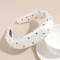 Dettaglio del cerchietto in raso bianco a pois neri fatto a mano su sfondo beige neutro - Bianco