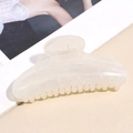 Macro detail of creamy white acetate hair claw clip showing marble pattern and metal spring - Milky White