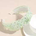 Dettaglio macro di un cerchietto in pizzo verde chiaro con strass luccicanti e nodo - Verde