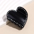 Gros plan d'une pince à cheveux cœur noir avec strass arc-en-ciel sur décor blanc - Noir