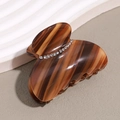 Detail of dark brown tortoiseshell hair claw clip with rhinestones on matte background - Tan