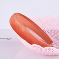 Dettaglio di una fascia per capelli in velluto arancione in un cesto rosa su sfondo bianco - Arancione