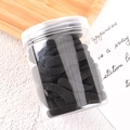 Close-up of high elasticity black hair ties packed in a transparent plastic jar - Black