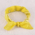 Dettaglio della fascia gialla con stampa paisley e nodo elegante su sfondo materico - Foulard Capelli Giallo