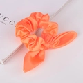 Detail eines leuchtend orangen Satin-Haargummis mit Hasenohren auf weißem Magazin - Orange