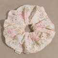 Detail van geborduurde bloemen scrunchie met maki-label en delicate stiksels - Roze