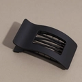 Détail d'une pince à cheveux noir mat avec design incurvé ajouré et dents de maintien - Noir
