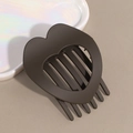 Macro shot of a matte dark brown heart-shaped hair clip on a white ceramic tray - Brown