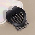 Detail view of heart-shaped matte black hair clip with comb teeth on beige background - Black