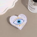 Detailed macro view of heart-shaped evil eye hair claw clip with white marble texture - Heart Evil Eye