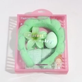 Detail view of light green spa headband and wristband set in a clear gift box packaging - Lily Flower Set / Green