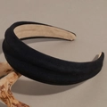 Detail of black suede padded headband with non-slip lining on a wooden stand - Black