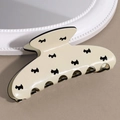 Gros plan d'une pince à cheveux crème avec motif terrier noir et finition brillante - Chien Beige