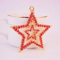 Golden double-layer star keychain with pink rhinestones on a white porcelain cup - Pink