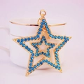 Double-layered star keychain with blue rhinestones and gold metal hanging on a white cup - Blue