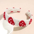 Detail eines handgehäkelten Stirnbands mit roten Erdbeermustern auf weißem Strickgewebe - Erdbeere Stirnband