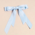 Details von hellblauer Satin-Haarschleife mit langen Bändern auf strukturiertem Grund - Himmelblau