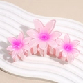Dettaglio macro della grande molletta per capelli con tre fiori di frangipane rosa - Rosa Rosso