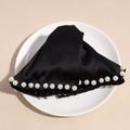 Detalle de pinza para el pelo en satén negro con perlas sobre un plato blanco - Negro