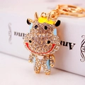 Llavero de vaca de dibujos animados con pedrería blanca brillante y acabados en metal dorado - Azul