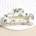 Macro shot of large rectangular hollow hair claw clip with cream floral pattern - Grey Flower