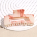 Detail view of large marble pink and cream acetate hair claw clip on white tray - Pink Ink Marble