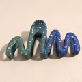 Close-up of wavy shark hair claw with blue-green gradient and starry night pattern - Gradient Blue Green