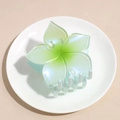 Macro detail of gradient green pearl flower claw clip on minimalist white display dish - Green