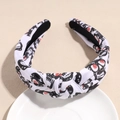 Detail view of white knotted headband with black skull patterns and red eye accents - Skeleton White