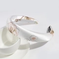 Detailed texture of white satin floral headband with a handmade label on a white cup - 3cm White