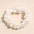 Detailed close-up of crystal beads and faux pearls on a flexible elastic hair band - White