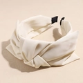Vue détaillée d'un serre-tête en satin crème avec un large nœud croisé et une finition texturée - Blanc laiteux
