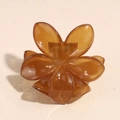 Macro view of a translucent amber resin flower hair claw clip on a textured background - Jelly Brown