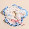 Dettaglio di scrunchie in tessuto con stampe di conigli rosa e bottone a fiore blu - Stampa Coniglio / Blu