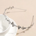 Detalle de la diadema de metal plateado con mariposas decorativas sobre una taza blanca - Mariposa / Plateado