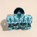 Gros plan d'une pince à cheveux en métal sarcelle avec un design élégant en forme d'onde - Vague Bleue