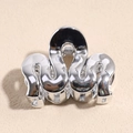 Vue macro d'une pince à cheveux argentée en forme de vague avec finition miroir et ressort - Argent Ondulé