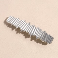 Dettaglio macro di un fermaglio per capelli argento con trama 3D ondulata e metallica - Quadrato Irregolare Argento