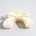 Vue détaillée d'une pince à cheveux en acétate blanc crème avec un design de nœud - Blanc Cassé